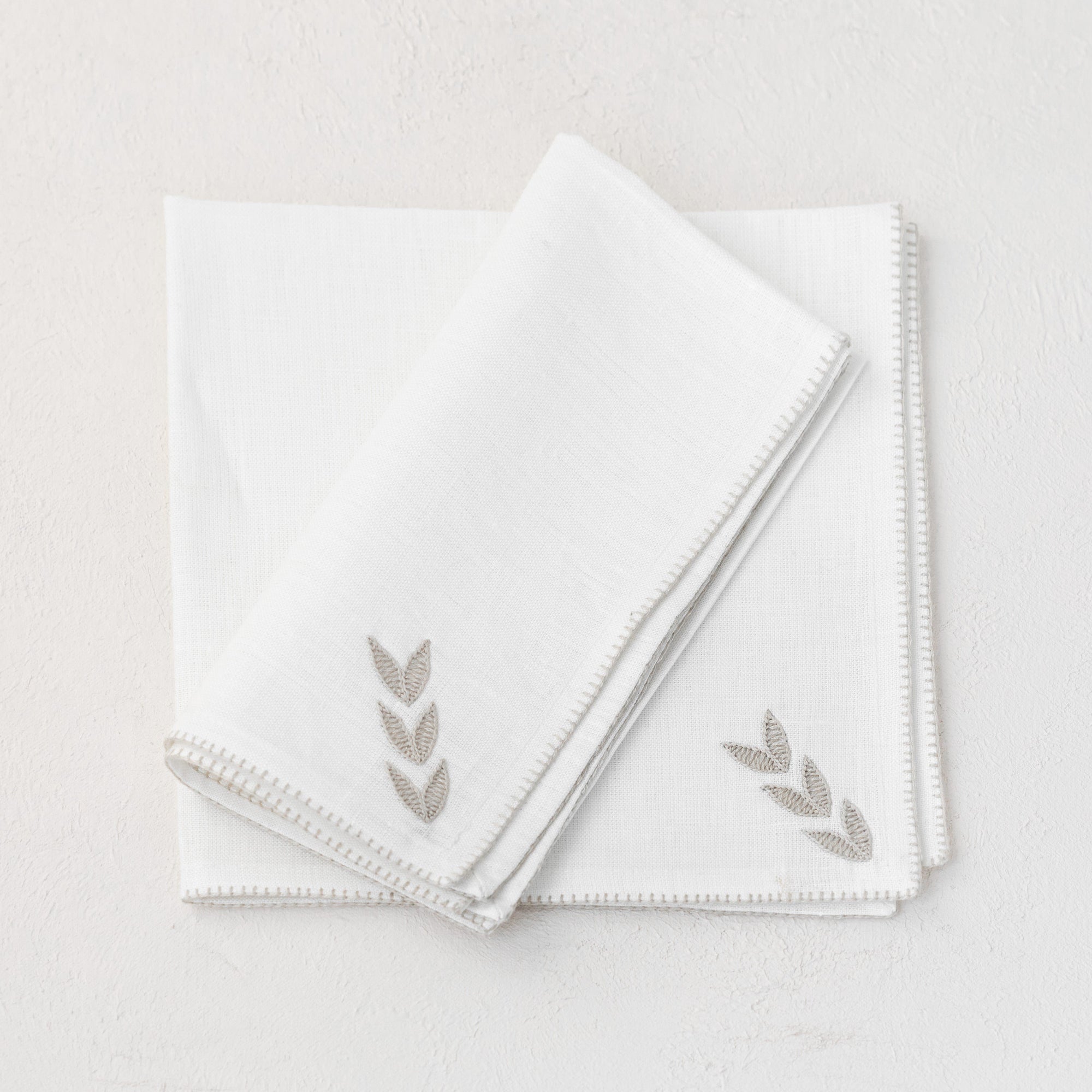 Cream linen napkin hand embroidered with a petal design by Artha Collections