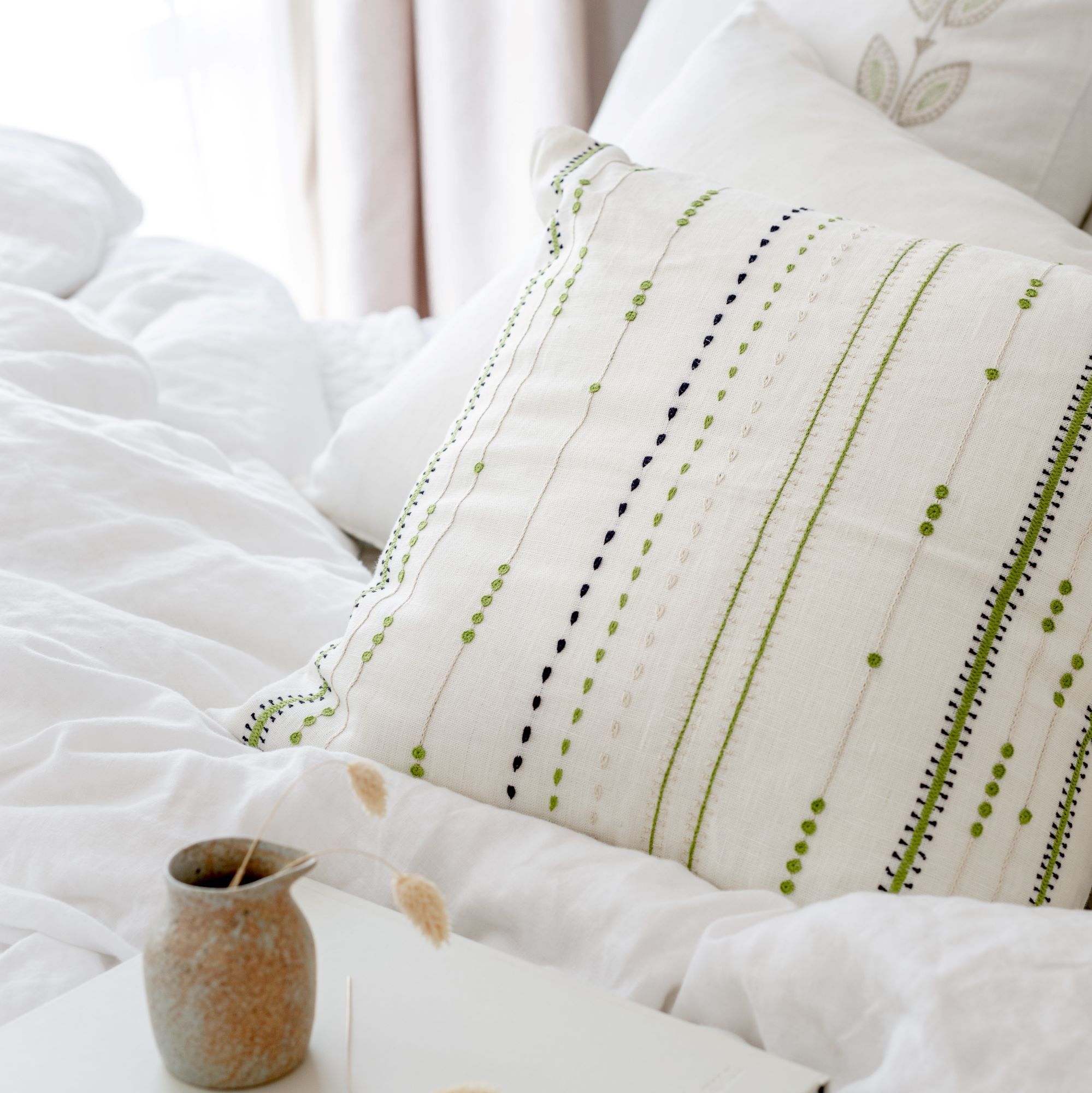 Cream linen hand embroidered throw pillow with bright green lines by Artha Collections